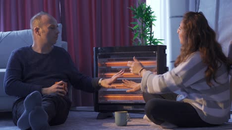 The-chilly-couple-are-warming-themselves-by-the-electric-heater.